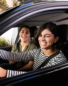 Two woman driving in car smiling